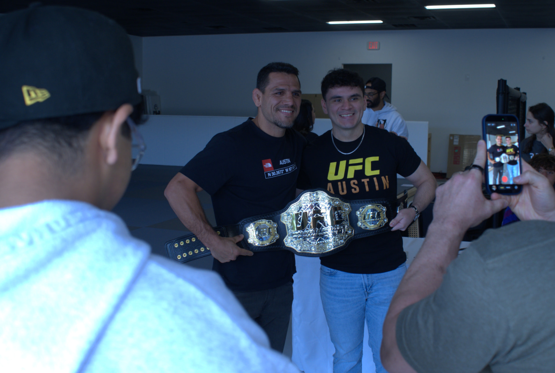 Two men holding a UFC championship belt at RDA Academy in Austin, Texas